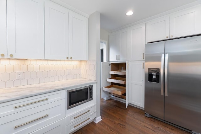 kitchen with appliances with stainless steel finishes, white cabinets, dark wood-type flooring, light stone countertops, and recessed lighting