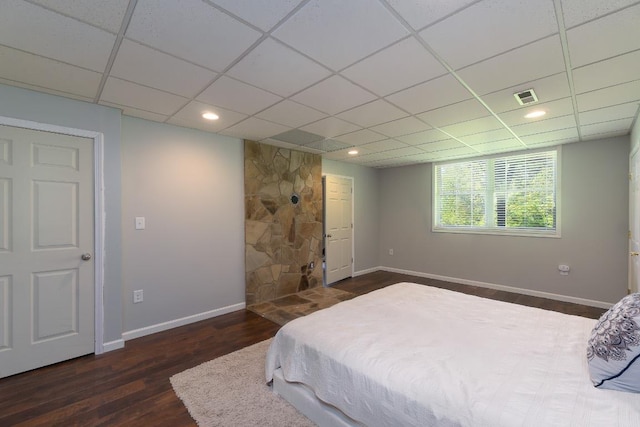 bedroom with baseboards, wood finished floors, and a paneled ceiling