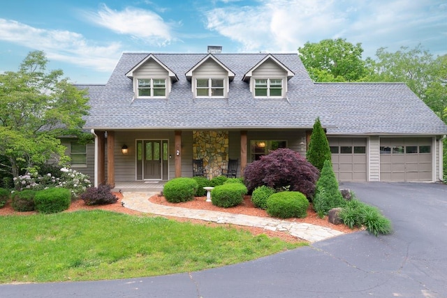 view of front of property with a porch, driveway, an attached garage, a shingled roof, and a front yard