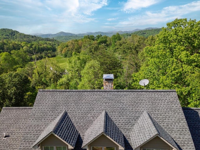 aerial view of property and surrounding area featuring a forest and a mountainous background