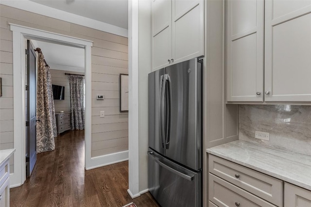 kitchen with dark wood-type flooring, stainless steel fridge, white cabinetry, light stone counters, and decorative backsplash