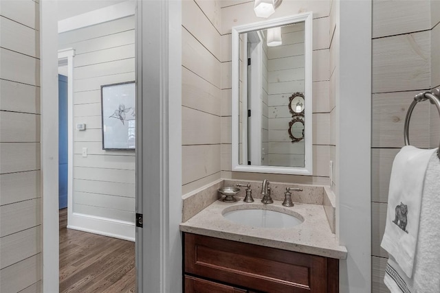 bathroom with vanity, wood-type flooring, and wood walls