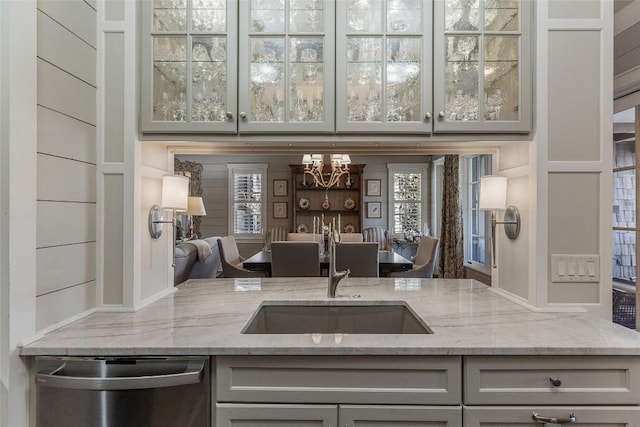 kitchen featuring light stone counters, sink, gray cabinets, and dishwasher