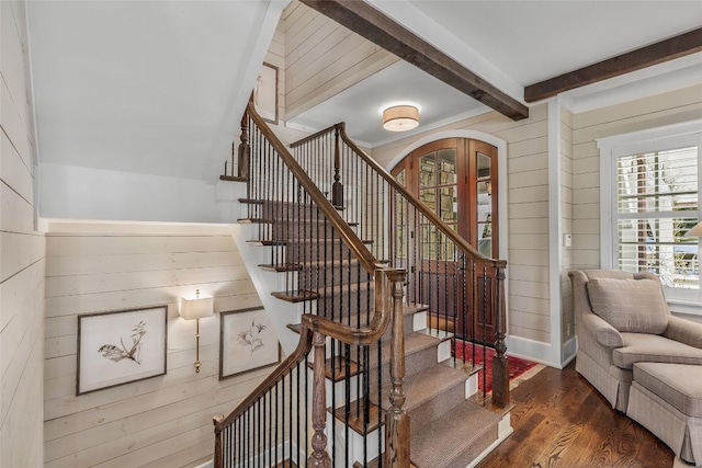 stairs featuring hardwood / wood-style flooring, wooden walls, and beamed ceiling