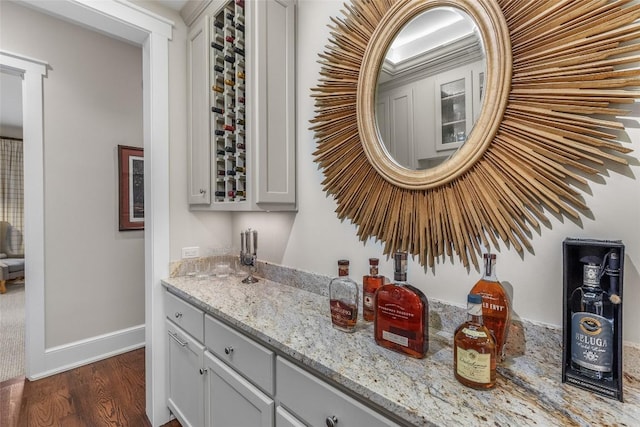 bar featuring white cabinetry, light stone countertops, and dark hardwood / wood-style floors