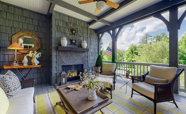 exterior space with ceiling fan, a fireplace, and beam ceiling