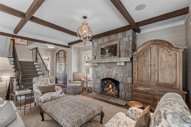 living room featuring a notable chandelier, a fireplace, beamed ceiling, and wood walls