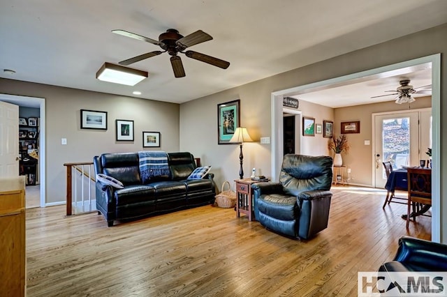 living room with baseboards, a ceiling fan, and wood finished floors