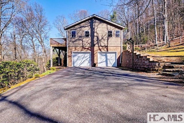 view of side of home with a garage, stairway, and driveway