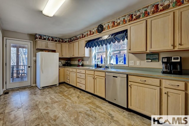 kitchen with a sink, stainless steel dishwasher, light brown cabinetry, and freestanding refrigerator
