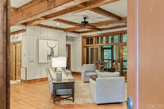 living room with beamed ceiling, ceiling fan, and light wood-type flooring