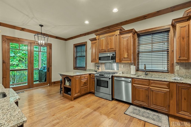 kitchen with sink, decorative light fixtures, stainless steel appliances, and light stone countertops