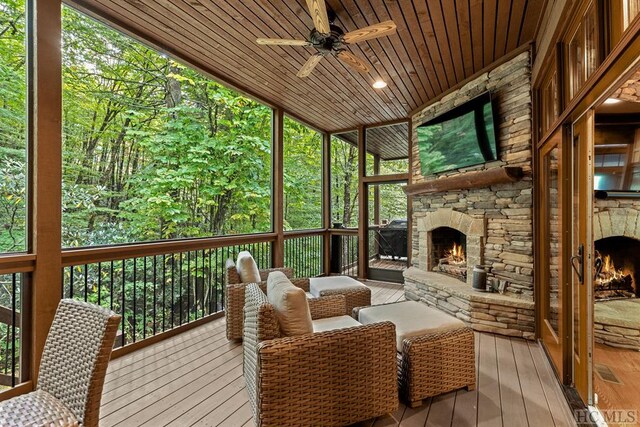 sunroom with ceiling fan, wooden ceiling, and an outdoor stone fireplace