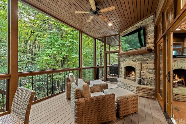 sunroom featuring a fireplace, ceiling fan, wood ceiling, and plenty of natural light