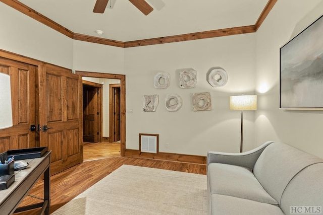 living room with ceiling fan, ornamental molding, and light wood-type flooring