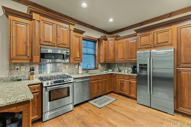 kitchen featuring sink, light stone counters, light hardwood / wood-style floors, stainless steel appliances, and crown molding