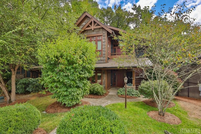 view of front of house featuring a balcony and a front yard