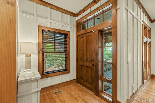 entryway featuring ornamental molding and light hardwood / wood-style flooring