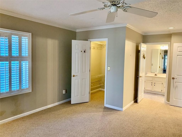 unfurnished bedroom featuring a spacious closet, light colored carpet, and crown molding