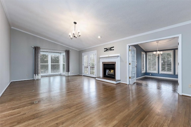 unfurnished living room with baseboards, a chandelier, lofted ceiling, a fireplace, and wood finished floors