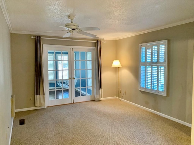 carpeted spare room with visible vents, french doors, a textured ceiling, and ornamental molding