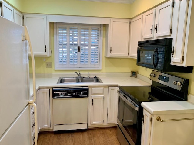 kitchen featuring light countertops, wood finished floors, white cabinets, white appliances, and a sink