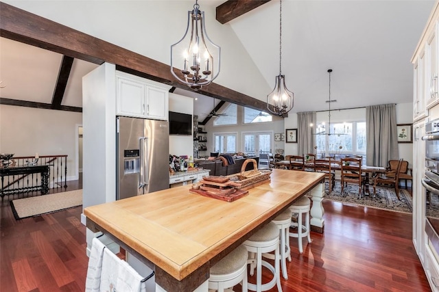 kitchen featuring stainless steel refrigerator with ice dispenser, dark wood finished floors, white cabinetry, and decorative light fixtures