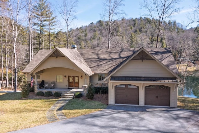 view of front of home with metal roof, covered porch, a front lawn, a standing seam roof, and a view of trees