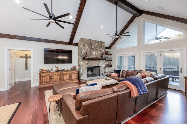 living room with a stone fireplace, dark wood-type flooring, a ceiling fan, and french doors