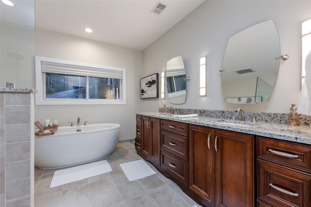 full bath with double vanity, a soaking tub, visible vents, and a sink