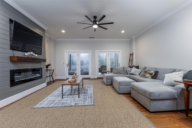 living area with ornamental molding, a fireplace, baseboards, and wood finished floors