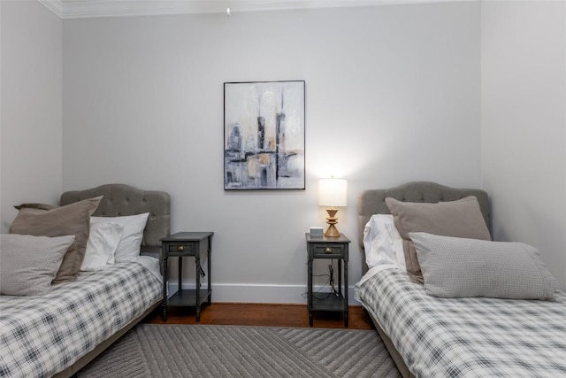 bedroom featuring baseboards, wood finished floors, and ornamental molding