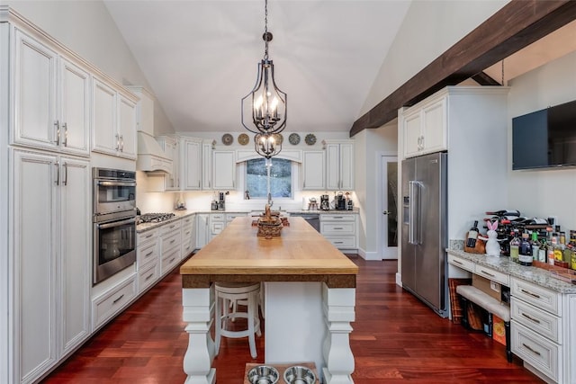 kitchen with dark wood-style floors, butcher block counters, appliances with stainless steel finishes, white cabinetry, and vaulted ceiling