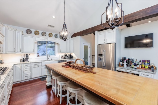 kitchen featuring a notable chandelier, butcher block counters, a sink, visible vents, and appliances with stainless steel finishes