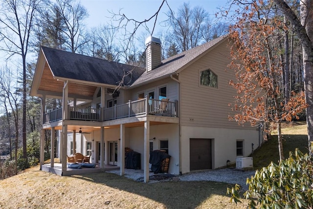 back of house with gravel driveway, a patio, a chimney, stucco siding, and a garage