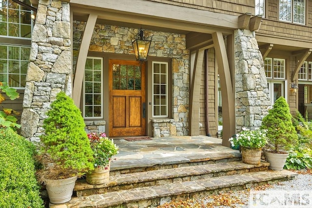 property entrance with a porch and stone siding