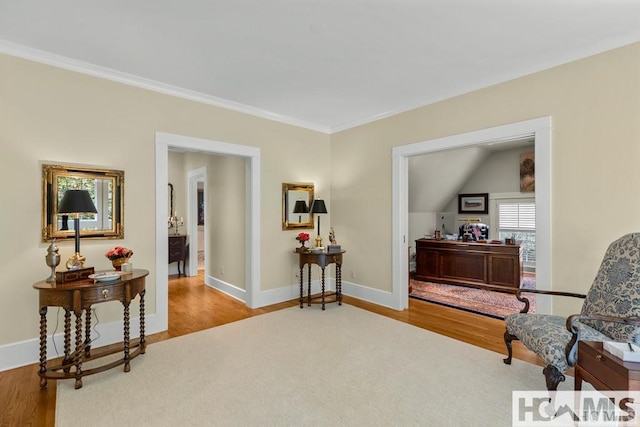 living area featuring wood finished floors, baseboards, and crown molding