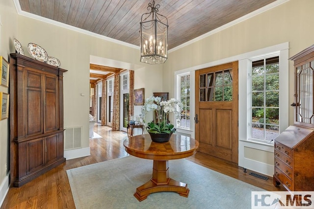 foyer featuring wood finished floors, a chandelier, baseboards, ornamental molding, and wooden ceiling