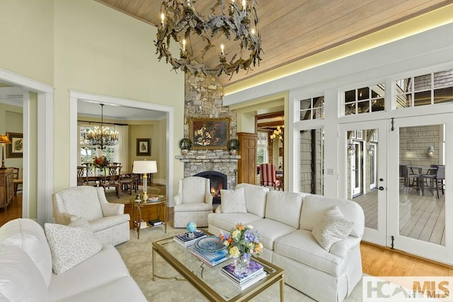 living area featuring a chandelier, a high ceiling, wood ceiling, a stone fireplace, and wood finished floors