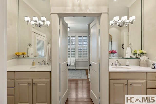 bathroom featuring a chandelier, two vanities, and wood finished floors