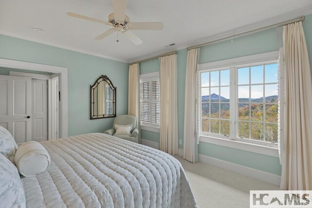 bedroom with carpet, baseboards, a ceiling fan, and a mountain view