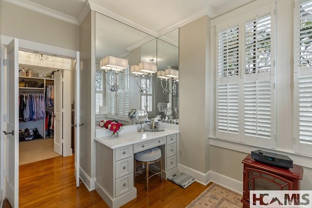bathroom with wood finished floors, ornamental molding, and baseboards