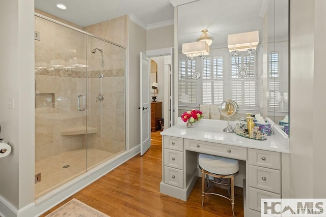 bathroom with ornamental molding, wood finished floors, a stall shower, and plenty of natural light