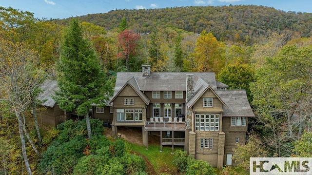 rear view of house featuring a view of trees and a wooden deck