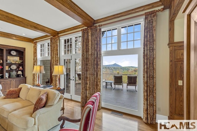 living room featuring beam ceiling, wood finished floors, healthy amount of natural light, french doors, and ornamental molding