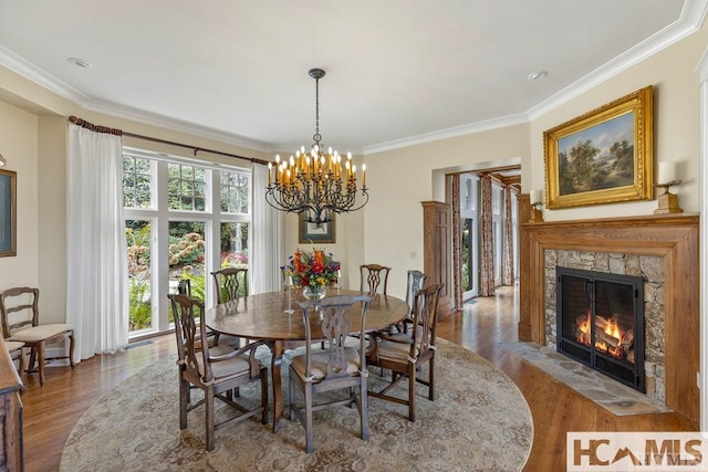 dining area with a chandelier, ornamental molding, wood finished floors, and a high end fireplace