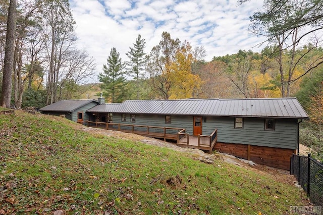 back of house with a wooden deck and a lawn