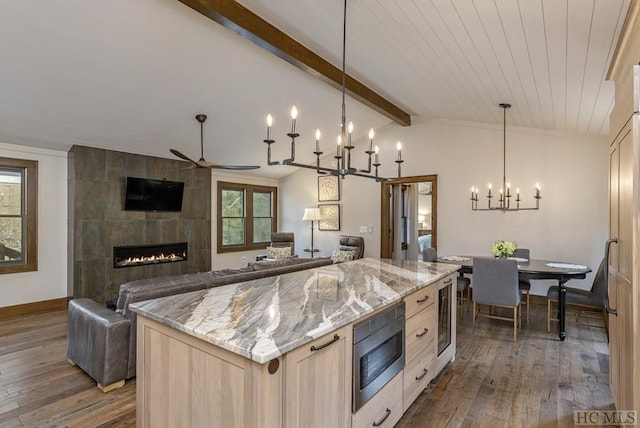 kitchen featuring a kitchen island, dark wood-type flooring, stainless steel microwave, and a fireplace