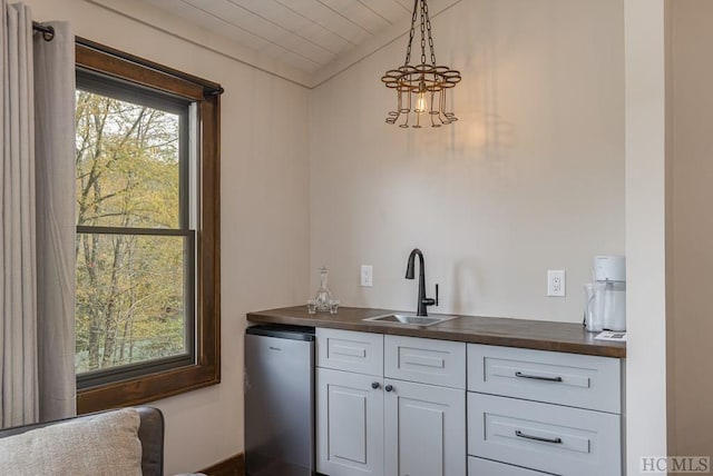 bar with butcher block counters, sink, refrigerator, hanging light fixtures, and white cabinets