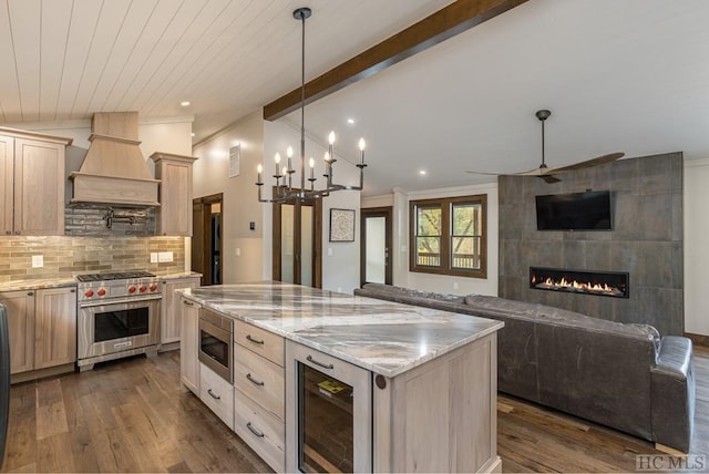 kitchen with vaulted ceiling with beams, stainless steel appliances, custom range hood, a kitchen island, and beverage cooler